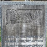 woman weeping by and image of the sun carved into a gravestone