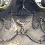 urn draped with wreaths carved on to cemetery gravestone