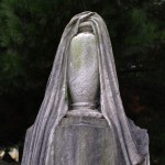 draped stone urn on top of cemetery gravestone