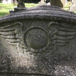 Egyptian winged disc symbol carved onto cemetery grave stone